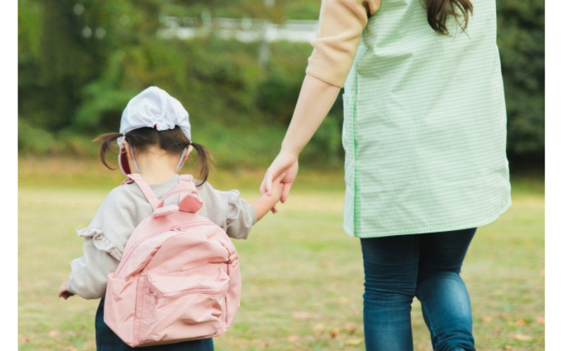 保育士と手をつなぐ2歳児の安心した様子