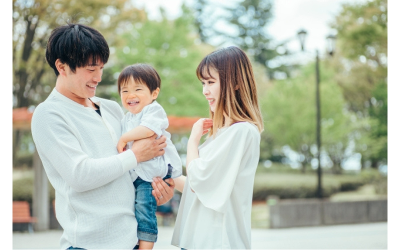 子どもを笑顔で抱っこする家族が、育児の負担を軽くしながら楽しく過ごしている様子